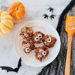 A plate of Halloween themed monster cookies with googly eyes in spooky setting.