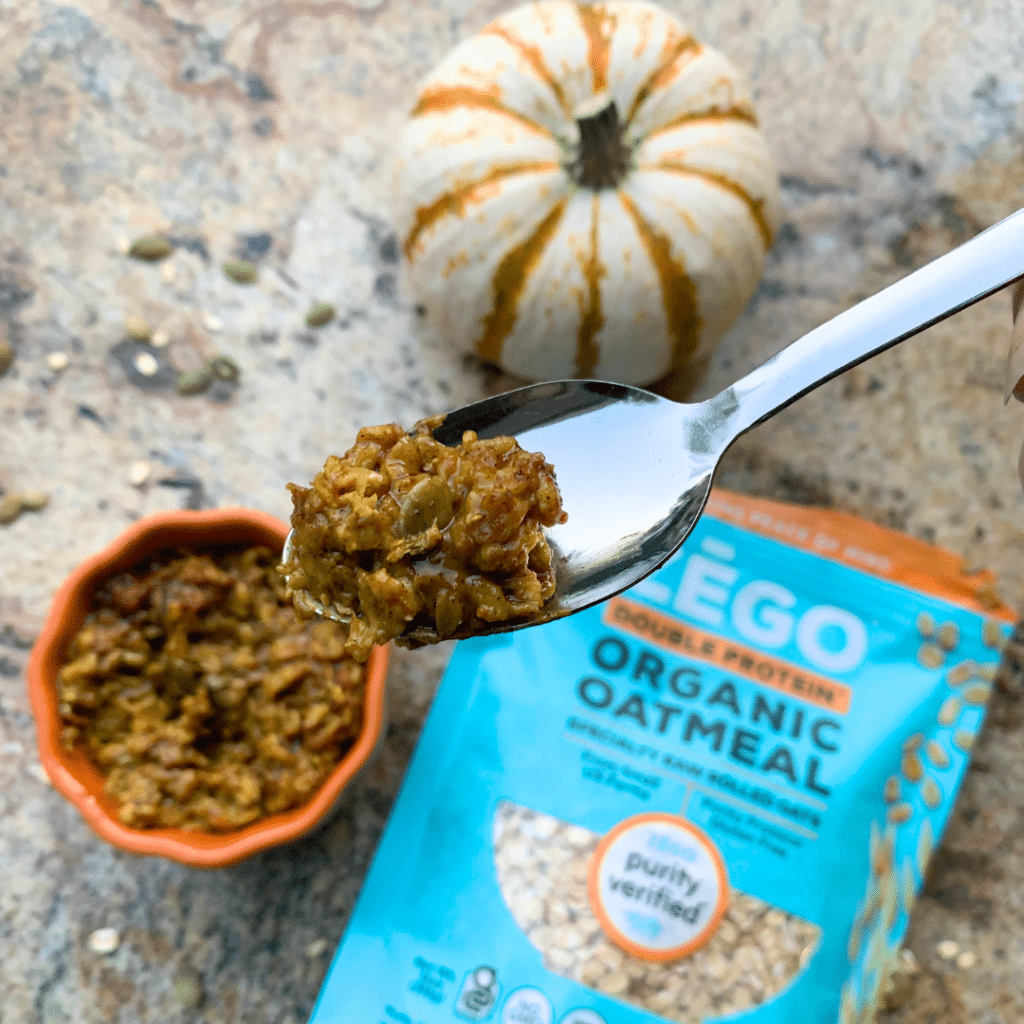 Spoonful of Anti Inflammatory Turmeric Pumpkin Oats. A bag of ZEGO Organic Double Protein Oats in the background.