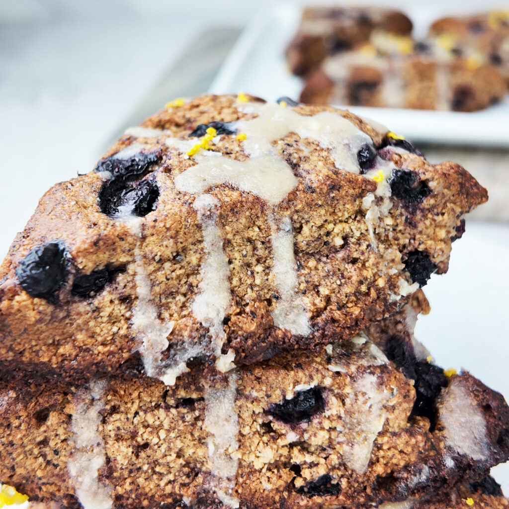 A close-up of a stack of gluten-free, vegan  blueberry lemon scones with fresh lemon zest